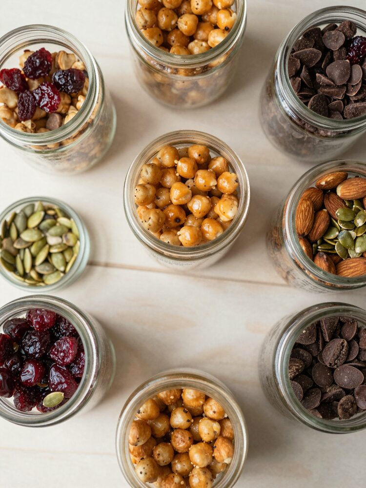 Small mason jars filled with high protein trail mix - roasted chickpeas, almonds, pumpkin seeds, cranberries and chocolate chips